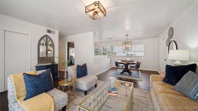 living room featuring ornamental molding, dark wood-type flooring, and an inviting chandelier