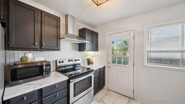 kitchen featuring decorative backsplash, appliances with stainless steel finishes, wall chimney range hood, crown molding, and dark brown cabinets