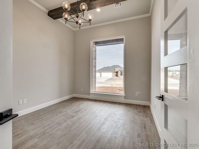 empty room featuring ornamental molding, wood-type flooring, and a chandelier