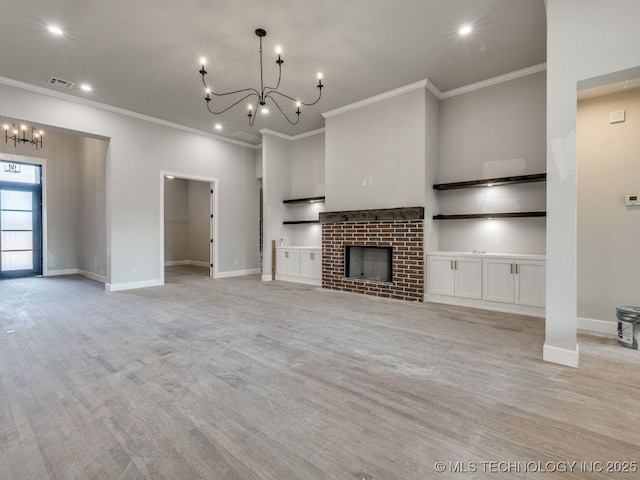 unfurnished living room featuring a brick fireplace, ornamental molding, and a chandelier