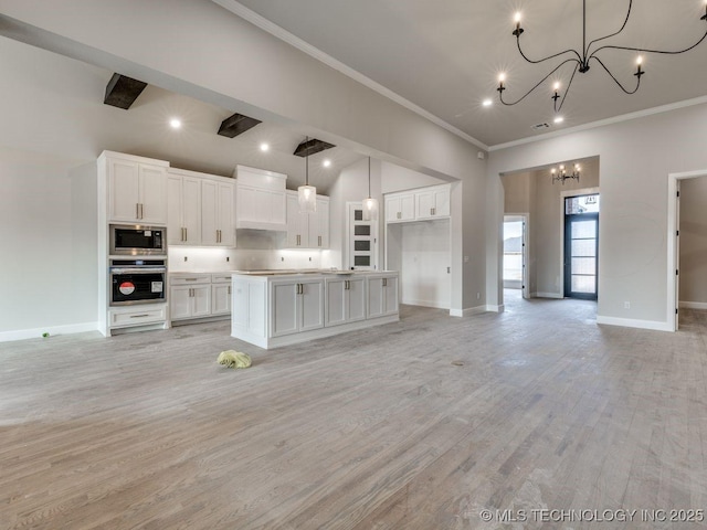 kitchen with white cabinetry, decorative light fixtures, a kitchen island, and appliances with stainless steel finishes