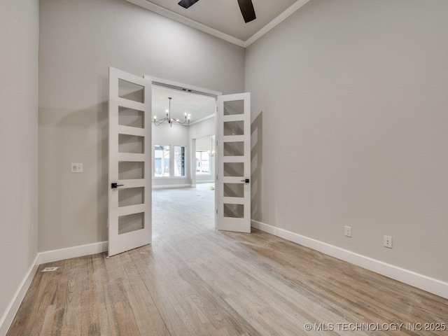 unfurnished room with crown molding, ceiling fan with notable chandelier, light hardwood / wood-style floors, and french doors