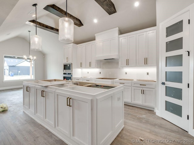 kitchen featuring white cabinetry, decorative light fixtures, light wood-type flooring, stainless steel appliances, and a kitchen island with sink