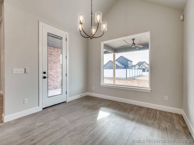 unfurnished dining area featuring hardwood / wood-style flooring, lofted ceiling, and ceiling fan with notable chandelier