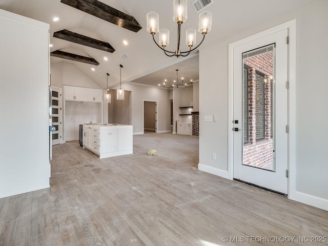 kitchen featuring an inviting chandelier, lofted ceiling with beams, a kitchen island, pendant lighting, and white cabinets