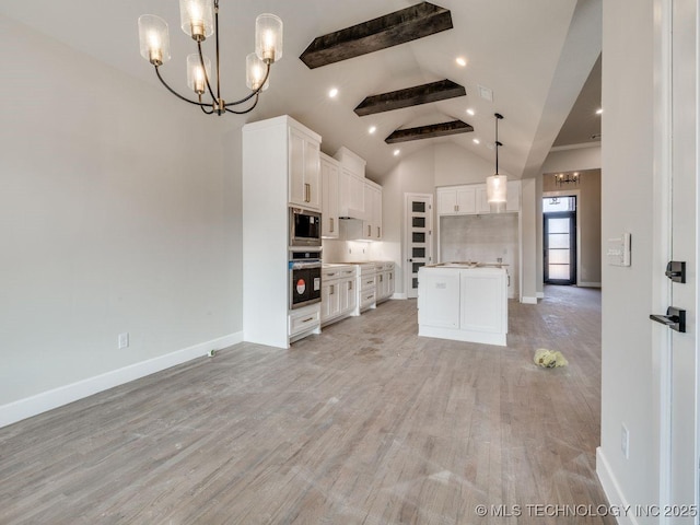 kitchen with decorative light fixtures, beamed ceiling, white cabinets, a center island, and stainless steel appliances