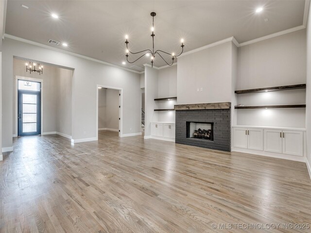 unfurnished living room featuring baseboards, visible vents, built in shelves, a notable chandelier, and crown molding