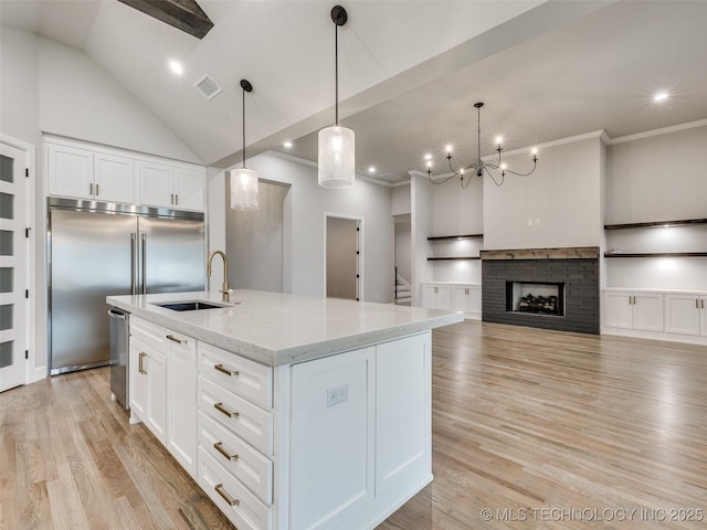 kitchen with built in fridge, a sink, visible vents, and light wood-type flooring