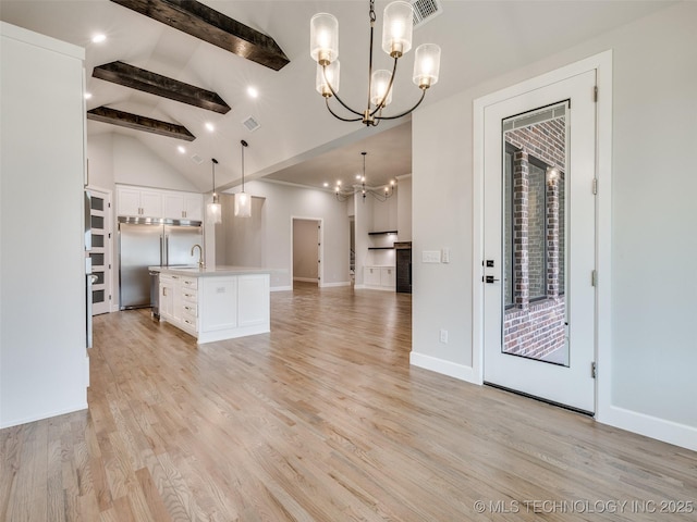 kitchen featuring a sink, open floor plan, a chandelier, white cabinets, and beam ceiling