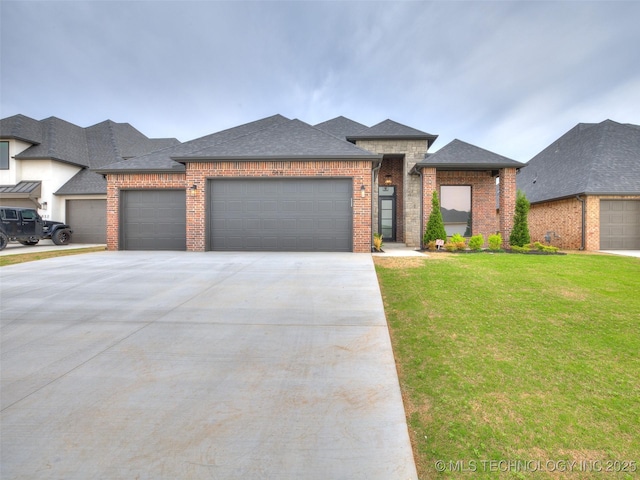 prairie-style house with a shingled roof, concrete driveway, an attached garage, brick siding, and a front yard