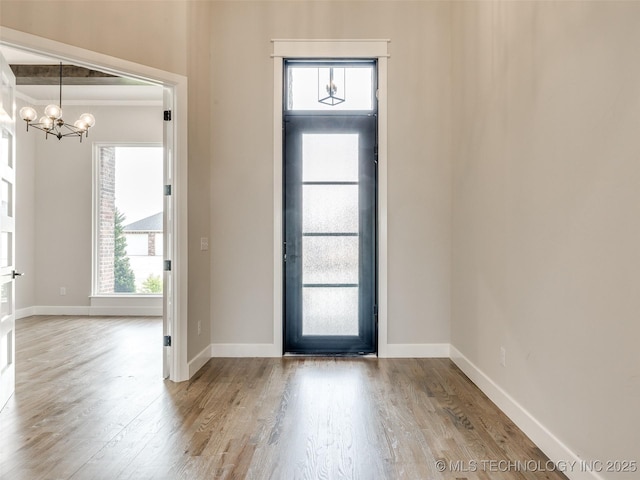 entrance foyer featuring wood finished floors, baseboards, and an inviting chandelier