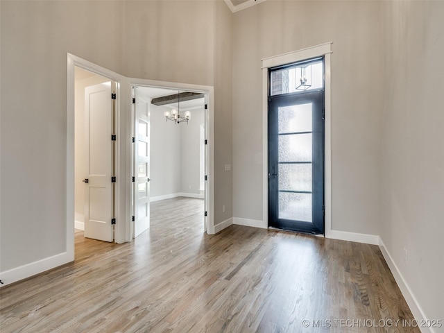 foyer entrance with baseboards, wood finished floors, a chandelier, and a high ceiling