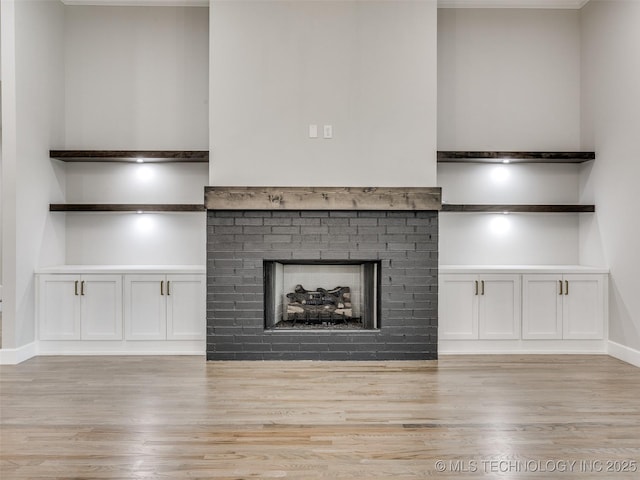 unfurnished living room featuring baseboards, a brick fireplace, and light wood-style flooring