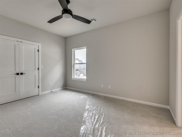 unfurnished bedroom with a closet, ceiling fan, carpet floors, baseboards, and visible vents