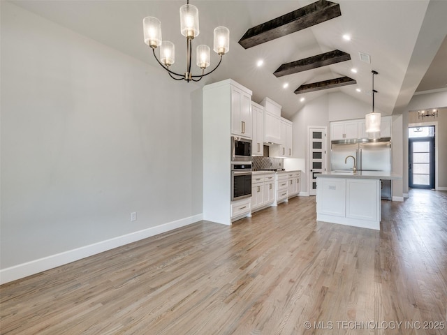 kitchen with white cabinets, beam ceiling, tasteful backsplash, an inviting chandelier, and built in appliances