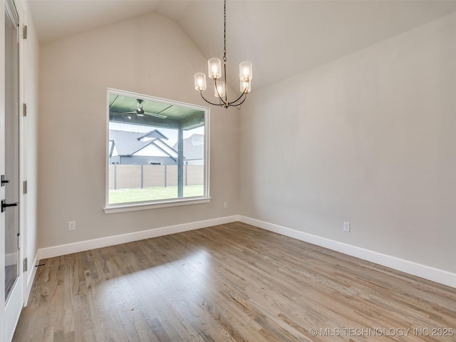 unfurnished room with lofted ceiling, baseboards, wood finished floors, and a chandelier