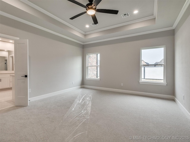 empty room featuring ornamental molding, ceiling fan, a tray ceiling, and light colored carpet