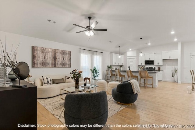 living room featuring ceiling fan, recessed lighting, visible vents, vaulted ceiling, and light wood finished floors