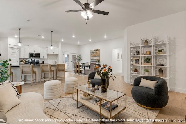 living area with recessed lighting, light wood-style flooring, a ceiling fan, vaulted ceiling, and baseboards