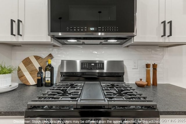 interior details with appliances with stainless steel finishes, dark countertops, white cabinetry, and decorative backsplash