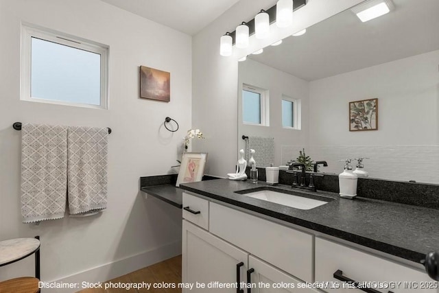 bathroom with baseboards, wood finished floors, vanity, and decorative backsplash