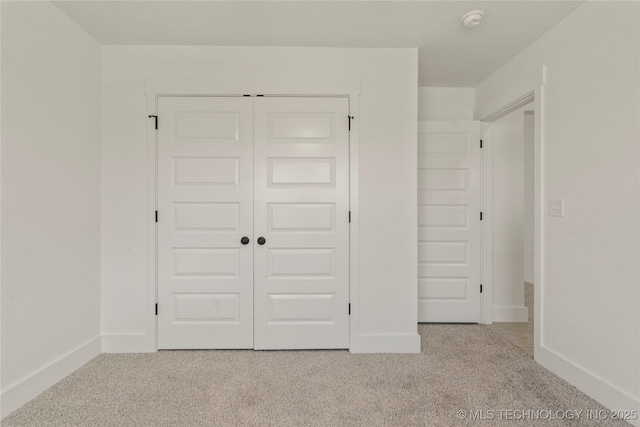 unfurnished bedroom featuring light colored carpet and a closet