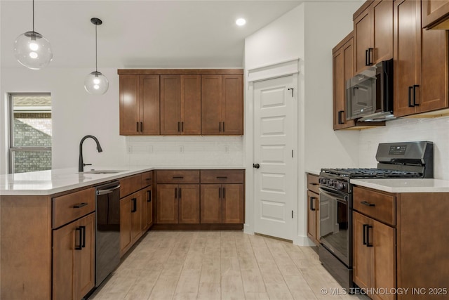 kitchen with decorative backsplash, sink, pendant lighting, and black appliances