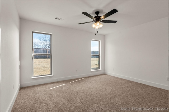 carpeted empty room with ceiling fan and a wealth of natural light