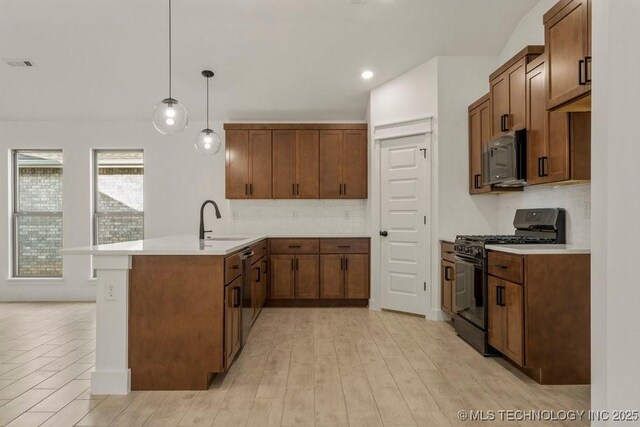 kitchen featuring black range with gas cooktop, hanging light fixtures, tasteful backsplash, and sink