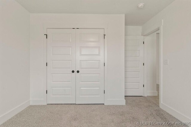 unfurnished bedroom featuring light colored carpet and a closet