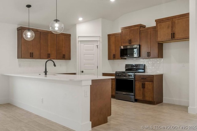 kitchen with vaulted ceiling, backsplash, hanging light fixtures, kitchen peninsula, and stainless steel appliances