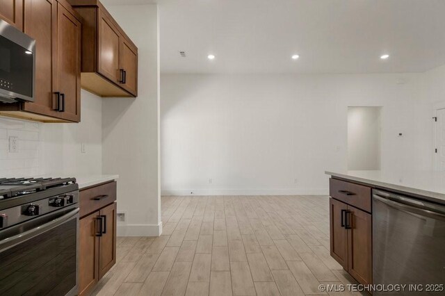 kitchen with appliances with stainless steel finishes, light wood-type flooring, and decorative backsplash