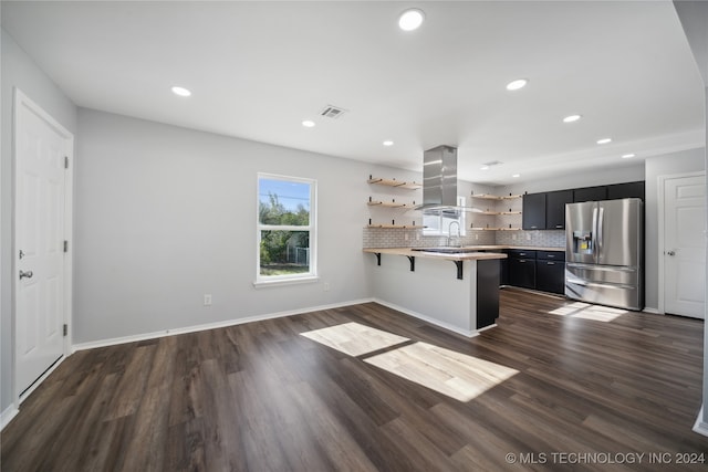 kitchen with a kitchen bar, stainless steel fridge, kitchen peninsula, tasteful backsplash, and dark hardwood / wood-style floors