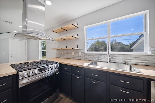 kitchen featuring butcher block countertops, stainless steel range with gas cooktop, tasteful backsplash, and island range hood