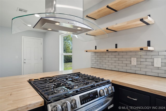 kitchen featuring decorative backsplash, island range hood, high end stainless steel range oven, and wood counters