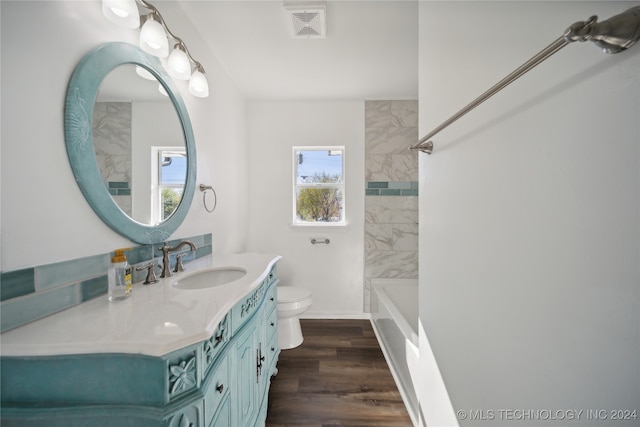 full bathroom featuring tiled shower / bath, hardwood / wood-style floors, vanity, and toilet