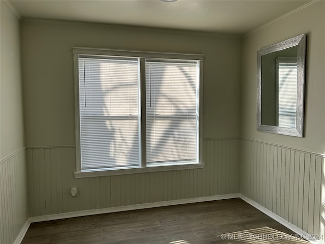 empty room featuring ornamental molding, dark wood-type flooring, and a healthy amount of sunlight