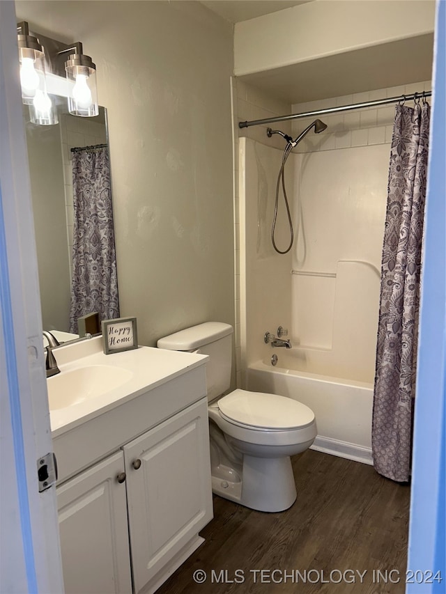 full bathroom with hardwood / wood-style floors, vanity, shower / tub combo with curtain, and toilet