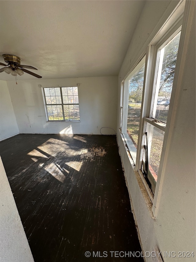 unfurnished room featuring ceiling fan, dark hardwood / wood-style flooring, and a wealth of natural light