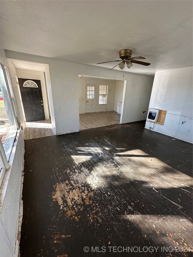 unfurnished living room with heating unit, ceiling fan, and hardwood / wood-style floors