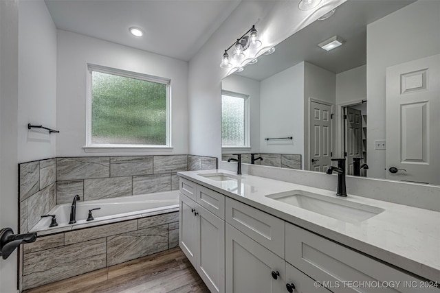 bathroom featuring vanity, hardwood / wood-style flooring, and tiled tub