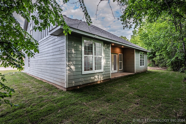 view of side of property with a patio and a lawn