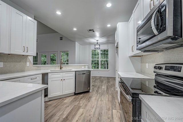 kitchen with light wood-type flooring, backsplash, stainless steel appliances, sink, and white cabinets