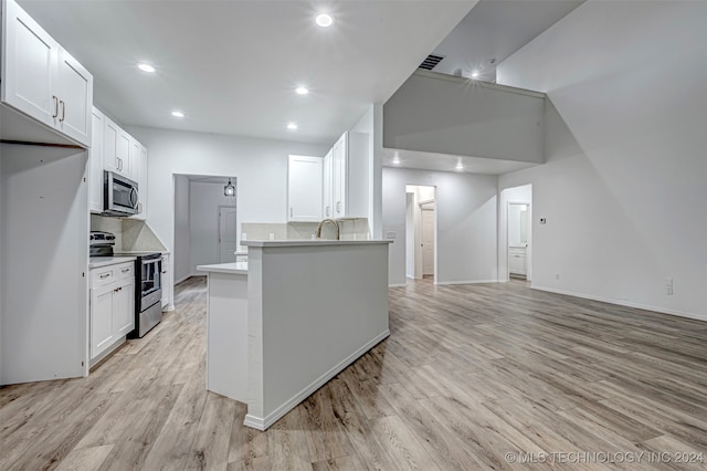 kitchen with sink, decorative backsplash, appliances with stainless steel finishes, light hardwood / wood-style floors, and white cabinetry