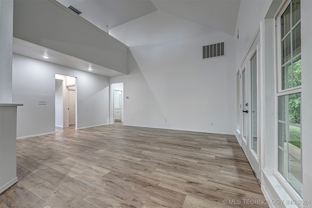 unfurnished room featuring light hardwood / wood-style floors, high vaulted ceiling, and a healthy amount of sunlight