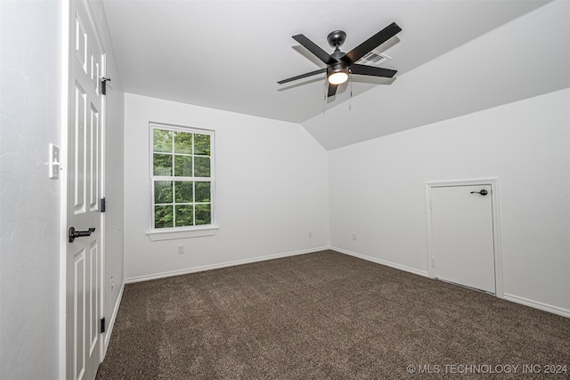 empty room with ceiling fan, lofted ceiling, and dark colored carpet