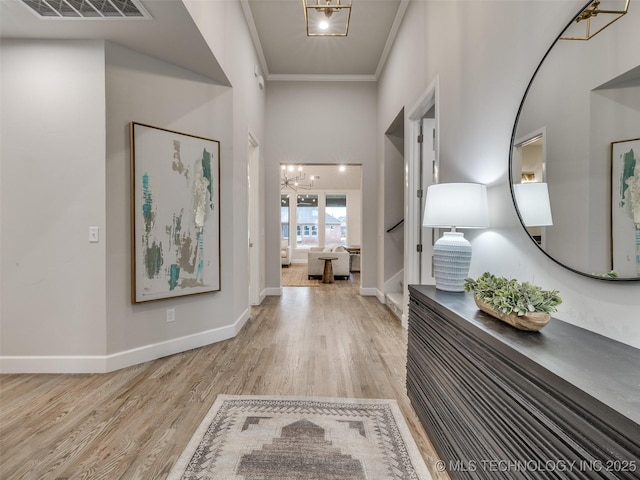 hallway featuring a notable chandelier, crown molding, and light hardwood / wood-style floors