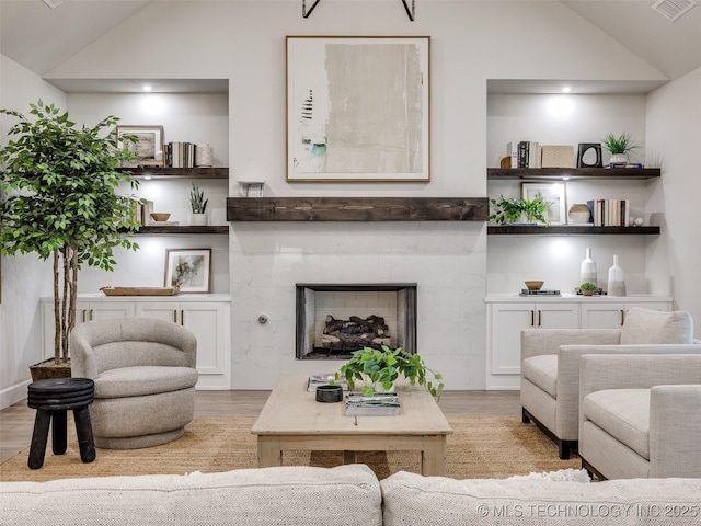 living room with lofted ceiling, a high end fireplace, and light hardwood / wood-style floors