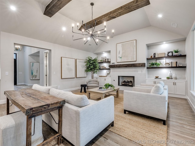 living room with lofted ceiling with beams, an inviting chandelier, and light hardwood / wood-style floors