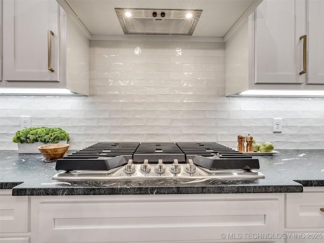 details featuring white cabinetry, tasteful backsplash, dark stone counters, and stainless steel gas cooktop